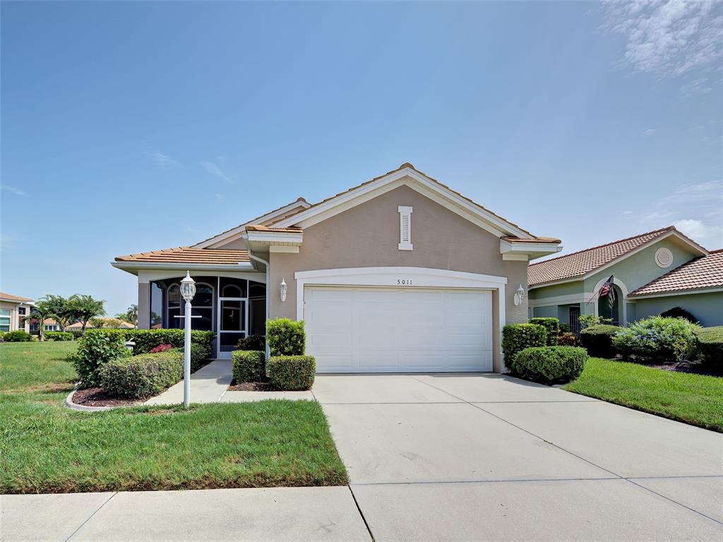 A single-story house with a beige stucco exterior, a white garage door, and a driveway — 5011 SEAGRASS DRIVE, VENICE, FL