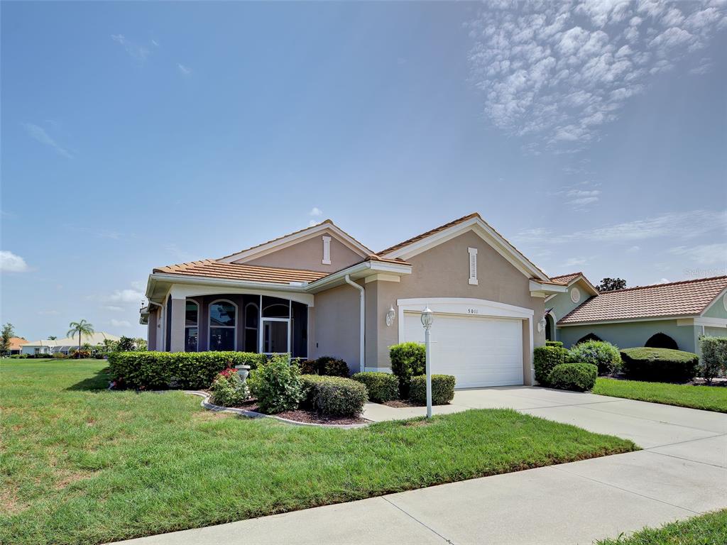 A single-story suburban house features a tan stucco exterior, a tiled roof, and a garage — 5011 SEAGRASS DRIVE, VENICE, FL