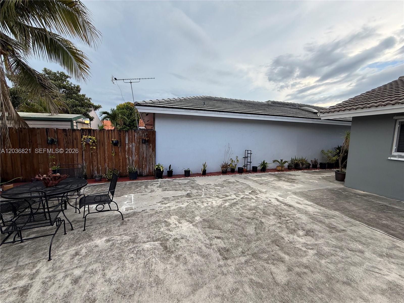 A concrete patio features a metal dining set and a row of potted plants — 14770 SW 60th St, Miami FL 33193, MIAMI, FL