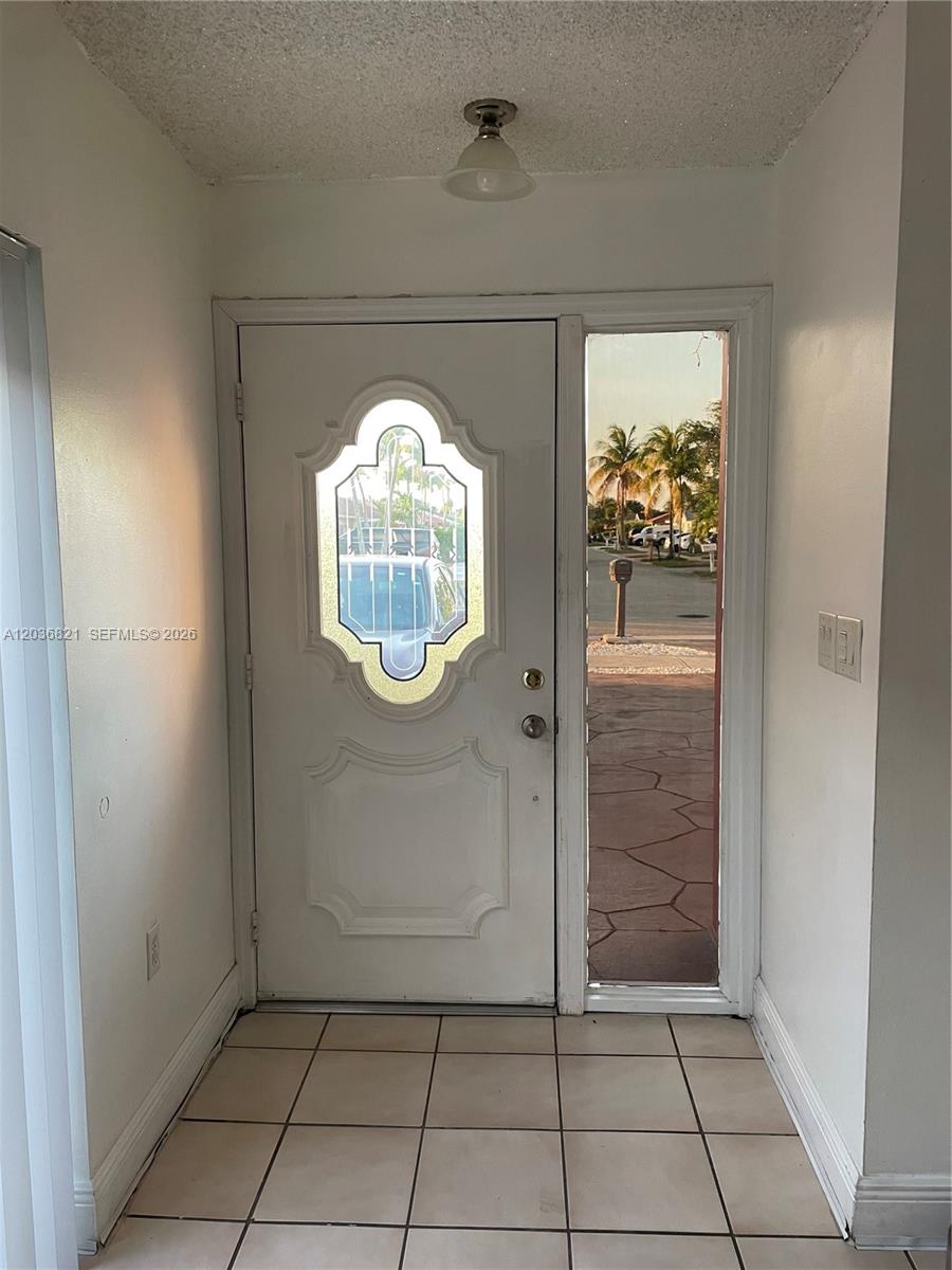 An entryway features a white front door with a decorative glass insert and tiled flooring — 14770 SW 60th St, Miami FL 33193, MIAMI, FL