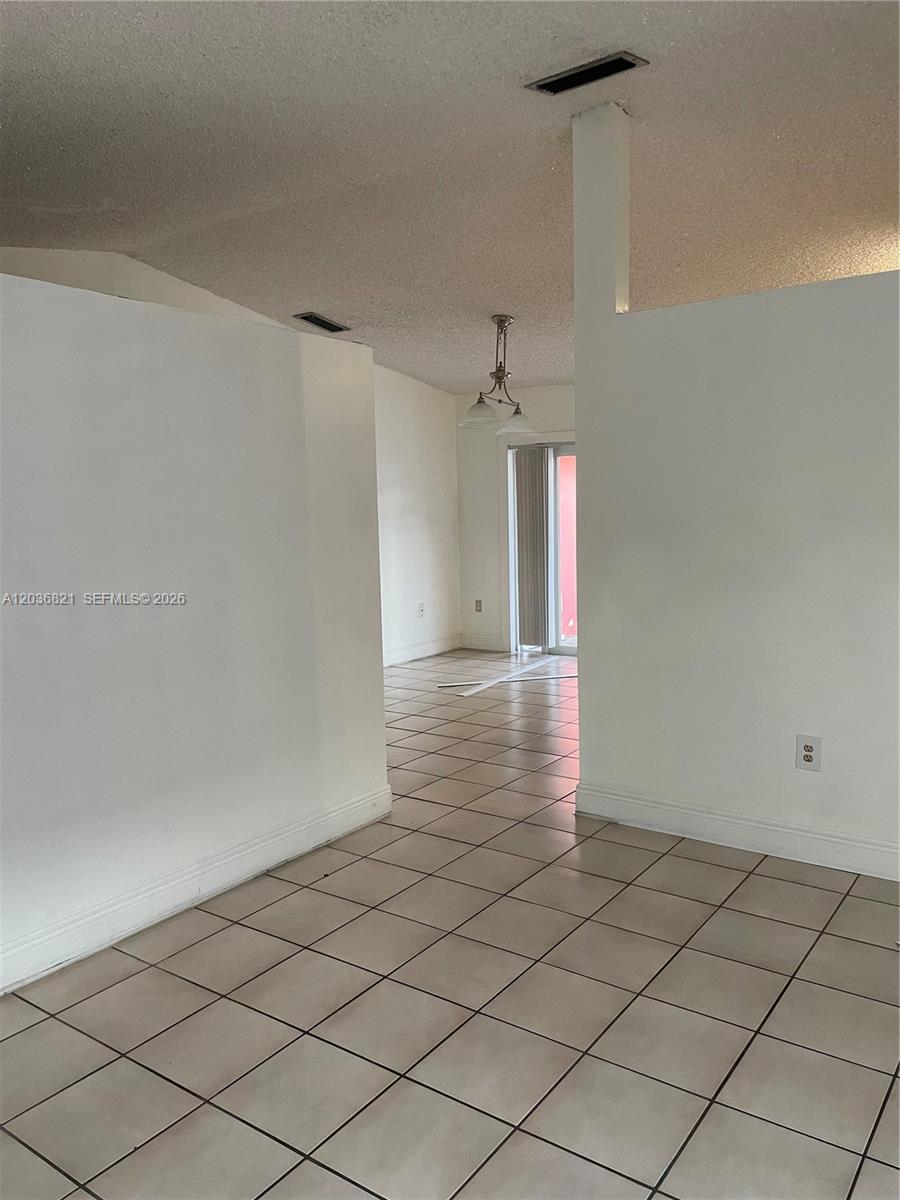 A tiled room leads through an opening to a dining area with a hanging light — 14770 SW 60th St, Miami FL 33193, MIAMI, FL