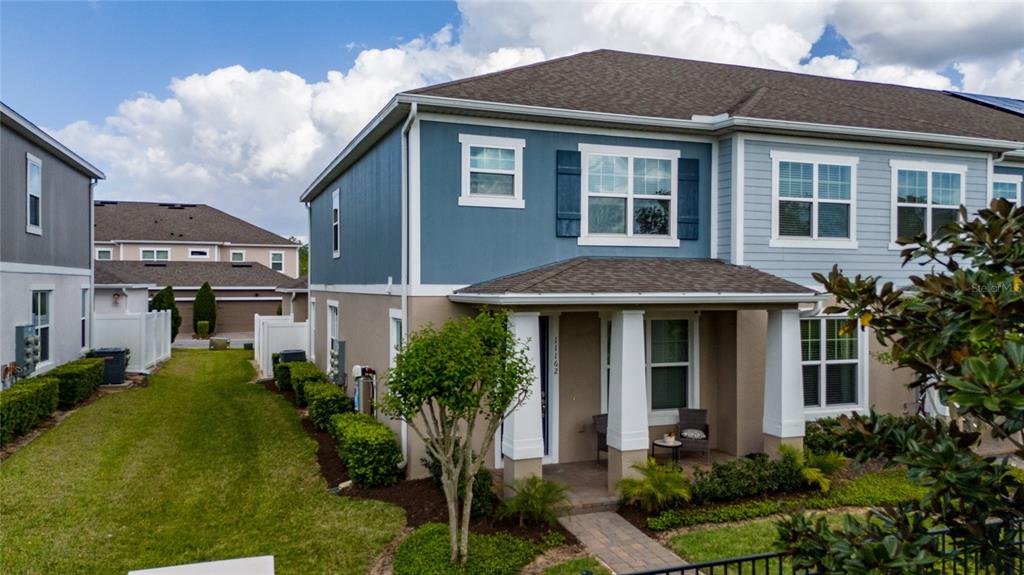 A two-story townhouse with blue and tan siding, a covered front porch, and a lawn — 11162 HANLON TERRACE ALLEY, WINTER GARDEN, FL