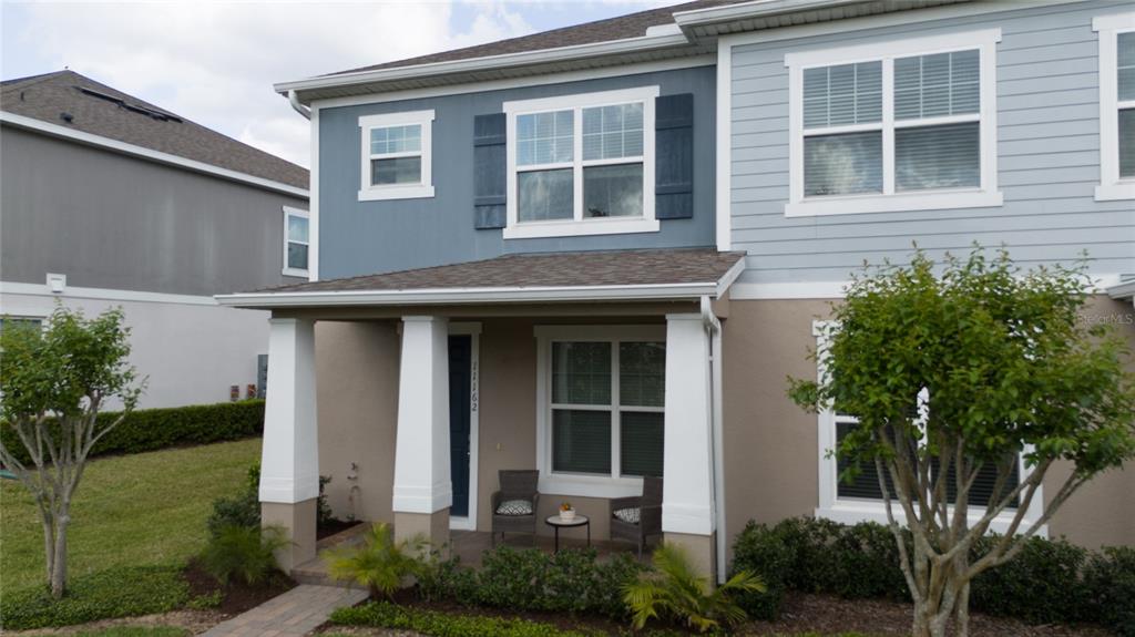 A two-story townhouse exterior features a covered front porch with white columns and blue siding — 11162 HANLON TERRACE ALLEY, WINTER GARDEN, FL