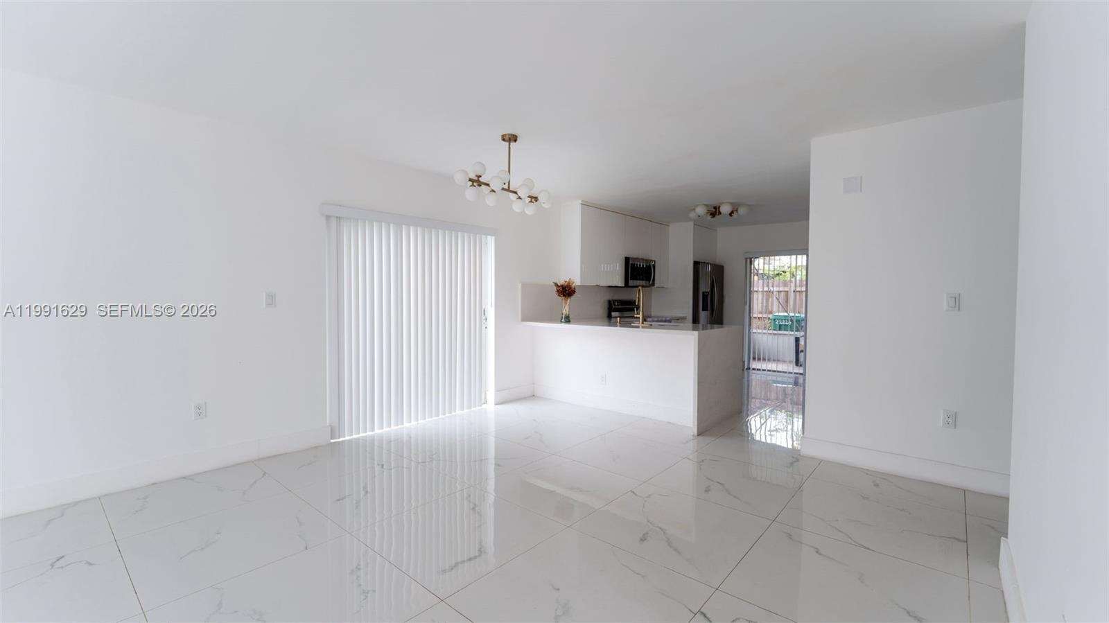 A bright, open-concept kitchen and dining area features white cabinetry and polished marble-look tile flooring — 22226 SW 98th Pl, Cutler Bay FL 33190, CUTLER BAY, FL