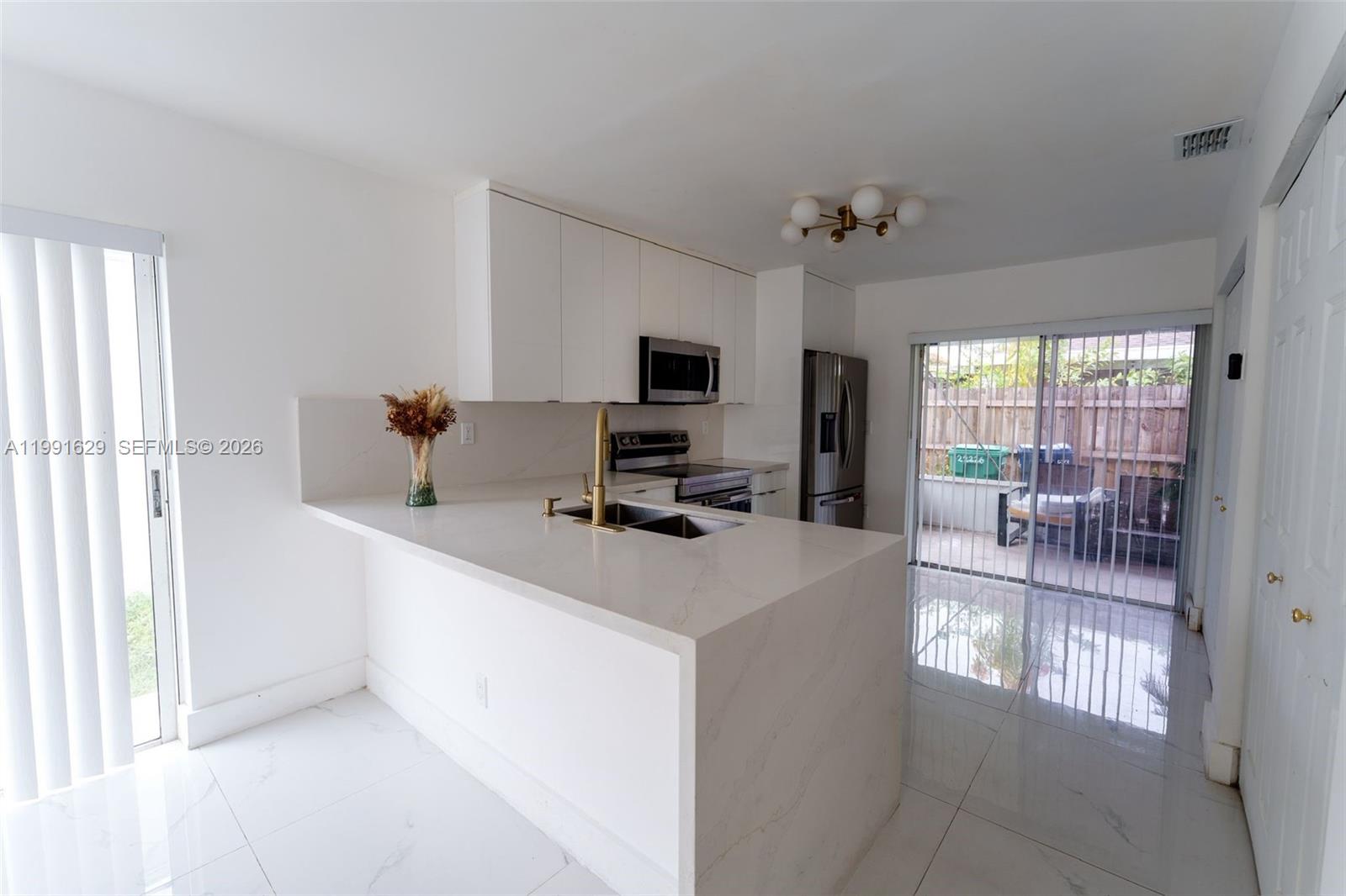 A modern kitchen features white cabinets, marble-look countertops, stainless steel appliances, and tile flooring — 22226 SW 98th Pl, Cutler Bay FL 33190, CUTLER BAY, FL
