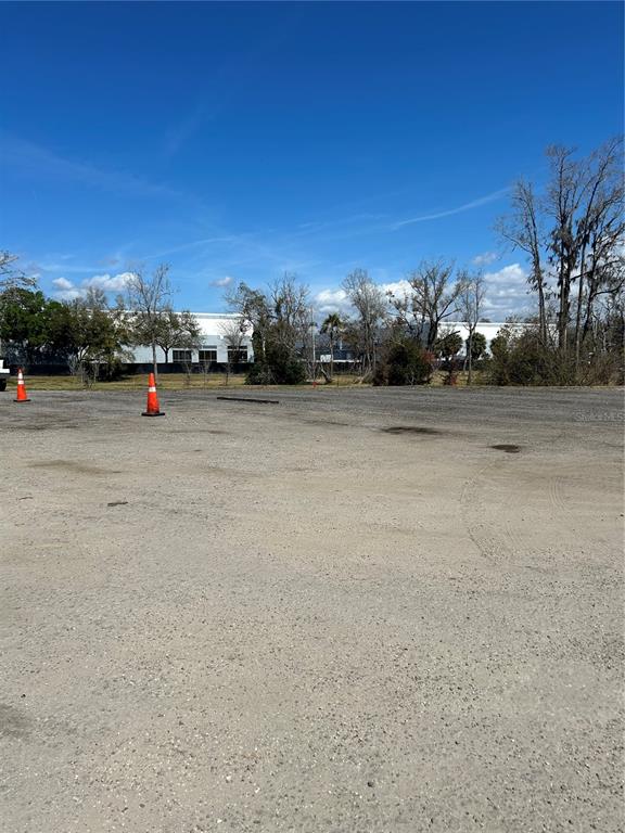 A large, unpaved gravel lot features two orange traffic cones under a clear blue sky — 6910 BENJAMIN ROAD, TAMPA, FL