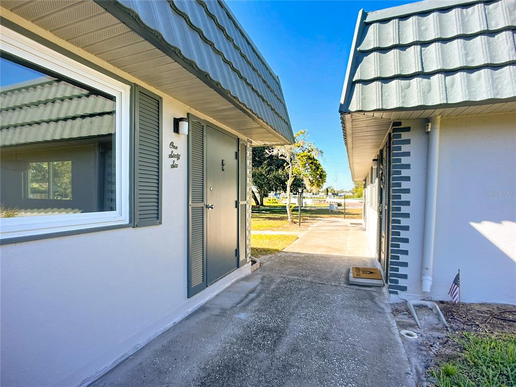 An exterior view shows the entrance to a unit with a gray door and shutters — 1811 BEDFORD LANE UNIT 166, SUN CITY CENTER, FL
