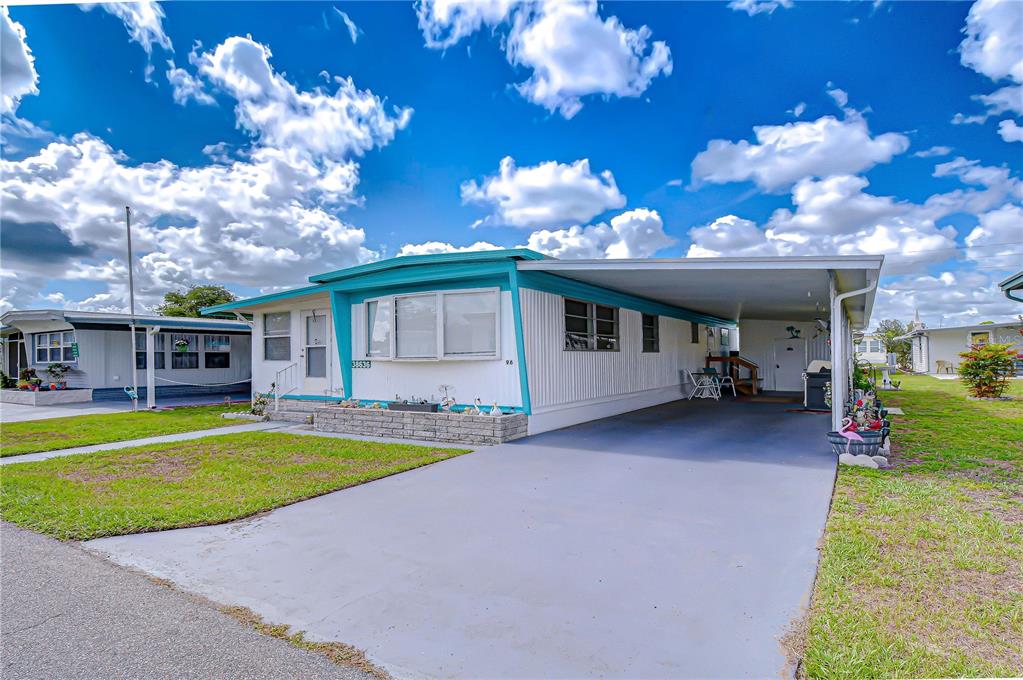 A single-story mobile home with white siding, teal trim, and an attached carport — 38636 REMORA AVENUE, ZEPHYRHILLS, FL