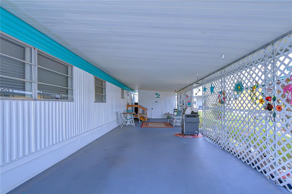 A covered patio features a gray floor, white siding, and a white lattice privacy screen — 38636 REMORA AVENUE, ZEPHYRHILLS, FL