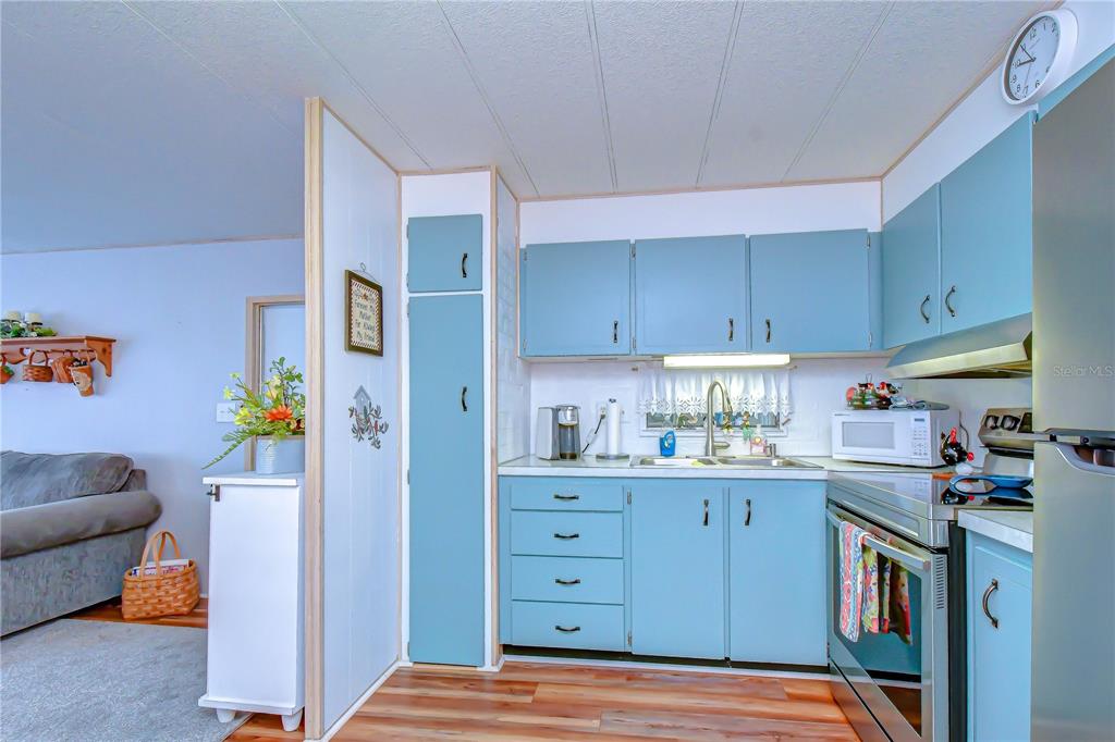 A kitchen features blue cabinets, a stainless steel stove, and a white microwave — 38636 REMORA AVENUE, ZEPHYRHILLS, FL