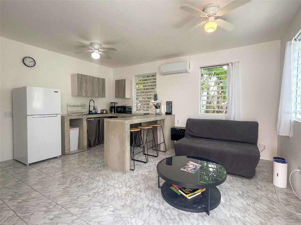 A studio apartment features a kitchen with concrete counters, a gray sofa, and tiled floors — 376 CALLE GIRASOL, VIEQUES, PR
