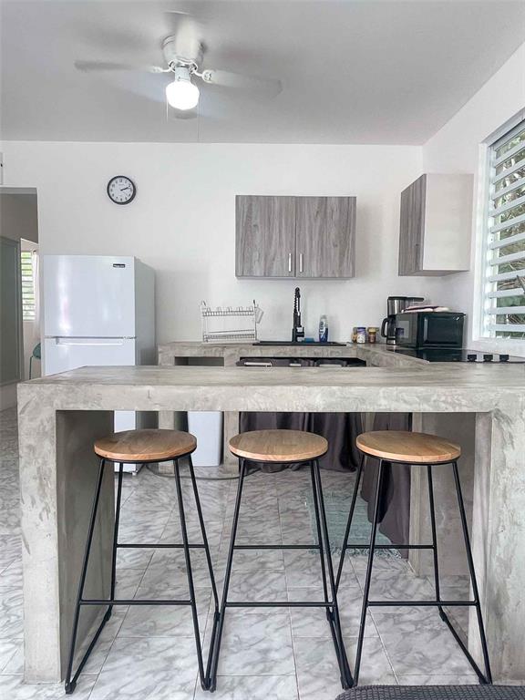 A kitchen features a concrete breakfast bar with three stools and light wood cabinets — 376 CALLE GIRASOL, VIEQUES, PR