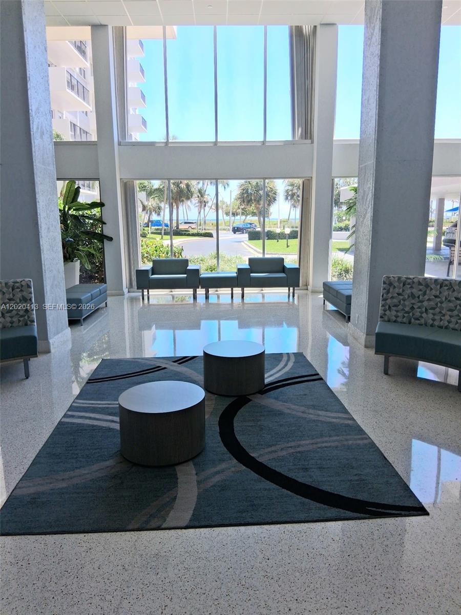 A bright lobby features floor-to-ceiling windows, modern seating, and a patterned area rug — 405 N Ocean Blvd # 1815, Pompano Beach FL 33062, POMPANO BEACH, FL