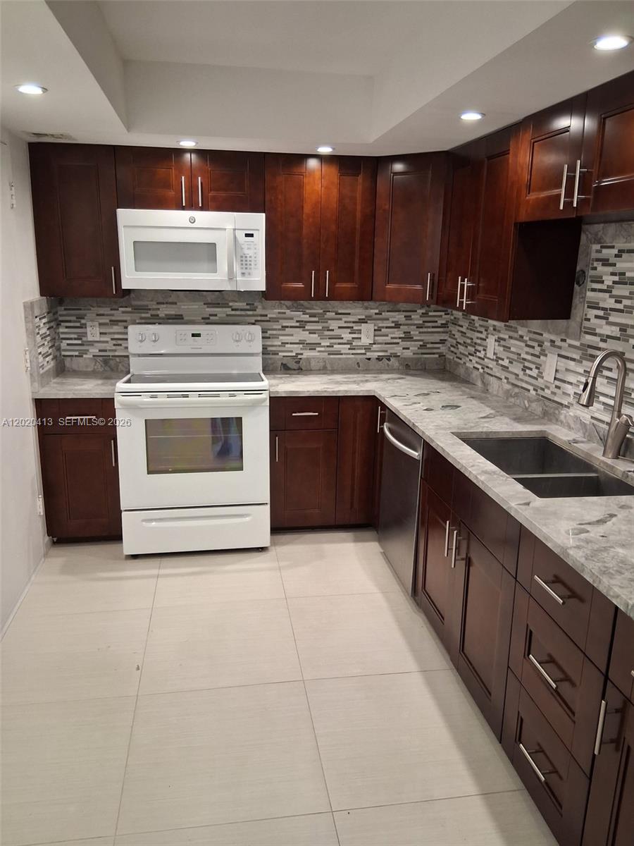 A kitchen features dark wood cabinets, white appliances, and gray patterned countertops — 405 N Ocean Blvd # 1815, Pompano Beach FL 33062, POMPANO BEACH, FL