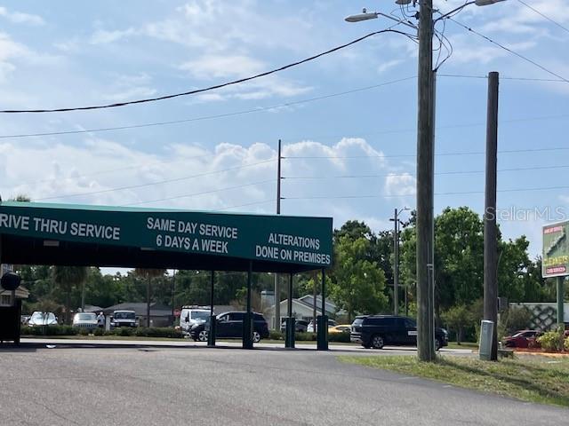 A green awning over a drive-thru service area displays business information in white text — 3501 / 3519 HENDERSON BOULEVARD, TAMPA, FL