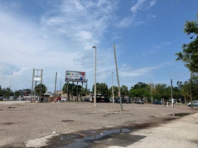 A large, paved, vacant parking lot features a billboard and utility poles under a blue sky — 3501 / 3519 HENDERSON BOULEVARD, TAMPA, FL
