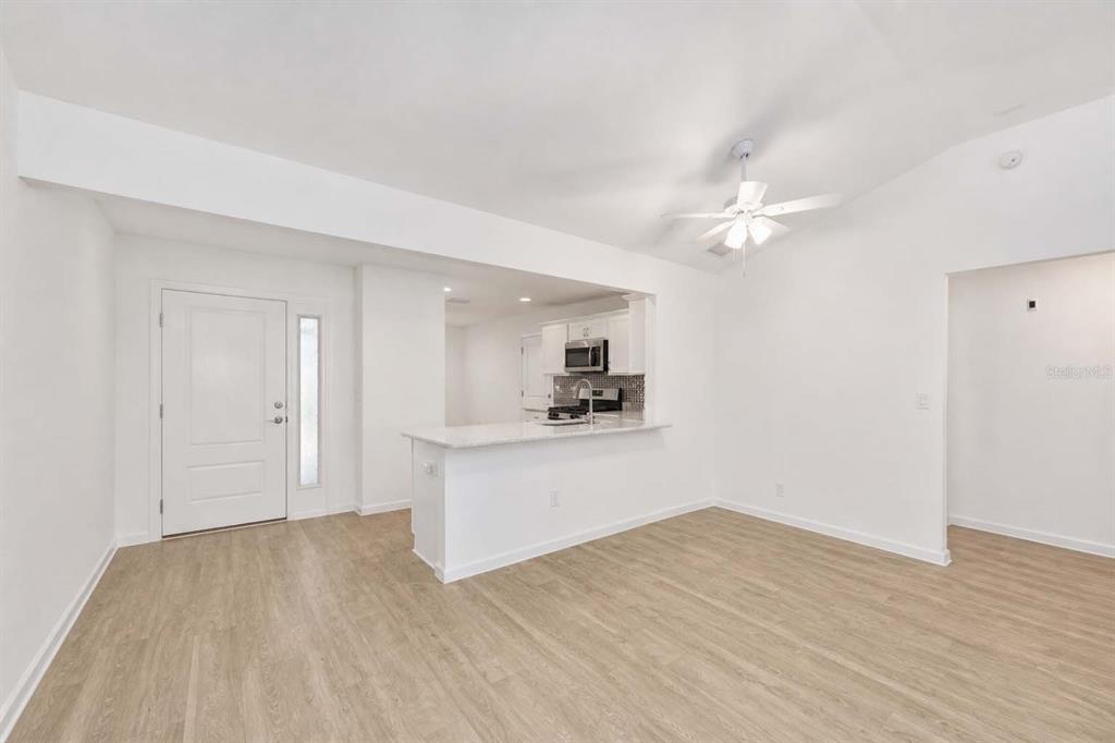 A bright, open-concept living area features light wood-look flooring and a kitchen breakfast bar — 1106 EBLING LOOP, THE VILLAGES, FL