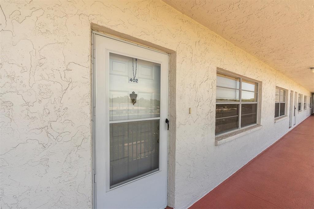 A white exterior door with number 402 and a window on a stucco building — 5060 76TH AVENUE N UNIT 402, PINELLAS PARK, FL