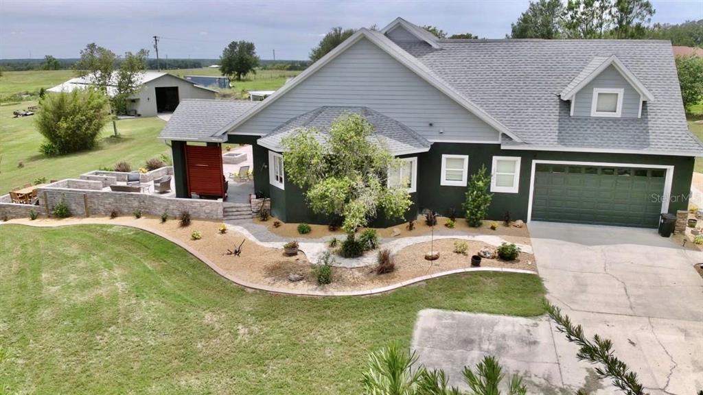 An aerial view of a house with a dark green exterior, gray roof, and stone patio — 32112 JACK RUSSELL COURT, DADE CITY, FL