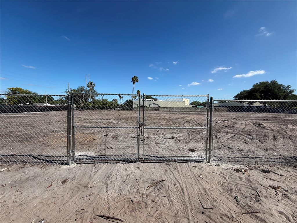 A chain-link fence with a closed gate surrounds a vacant, cleared dirt lot — 503 N JOHN YOUNG PARKWAY, ORLANDO, FL