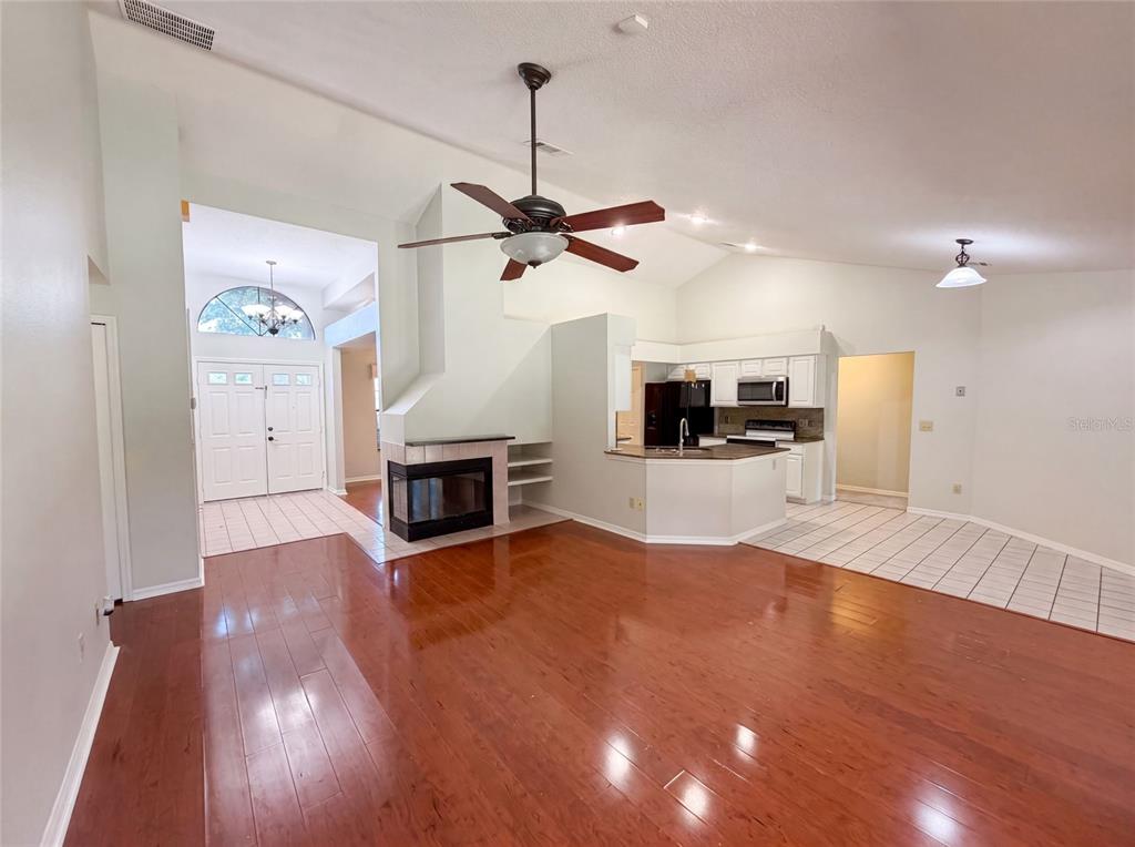 A living room with hardwood floors, a fireplace, and an open kitchen with white cabinets — 332 SPRUCEWOOD ROAD, LAKE MARY, FL