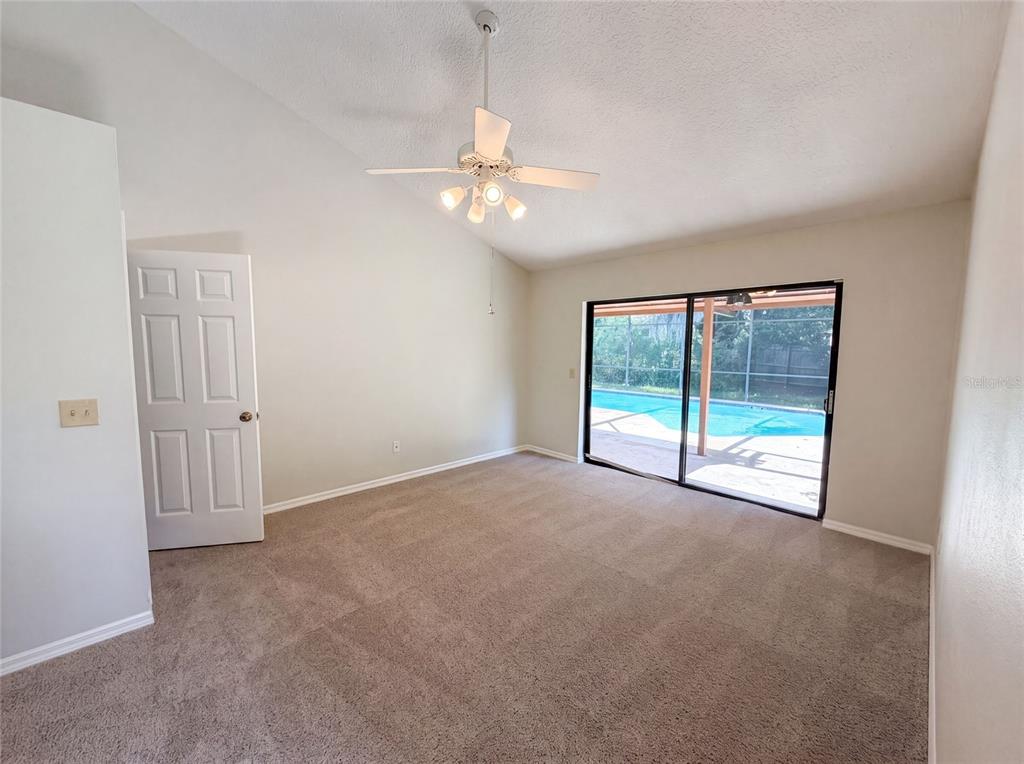 A carpeted bedroom features a vaulted ceiling, a ceiling fan, and sliding glass doors to a pool — 332 SPRUCEWOOD ROAD, LAKE MARY, FL