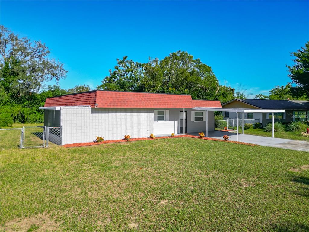 A single-story house with a red mansard roof, white siding, and an attached carport — 46 LAKE COURT LOOP, OCALA, FL