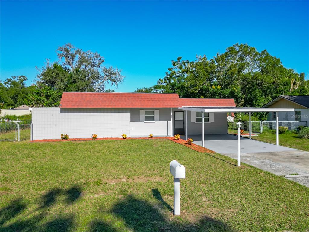 A single-story house with a red roof, gray siding, and an attached carport — 46 LAKE COURT LOOP, OCALA, FL