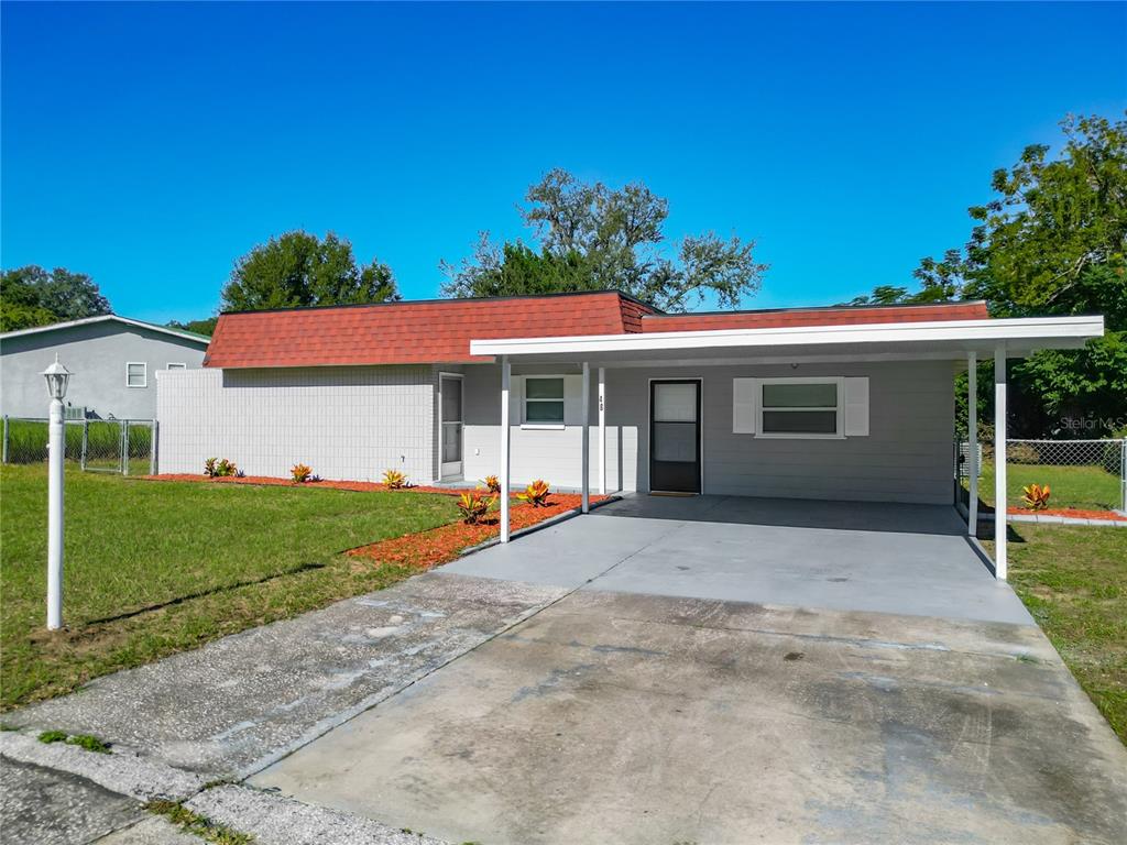 A single-story house with a red mansard roof, gray exterior, and an attached front carport — 46 LAKE COURT LOOP, OCALA, FL