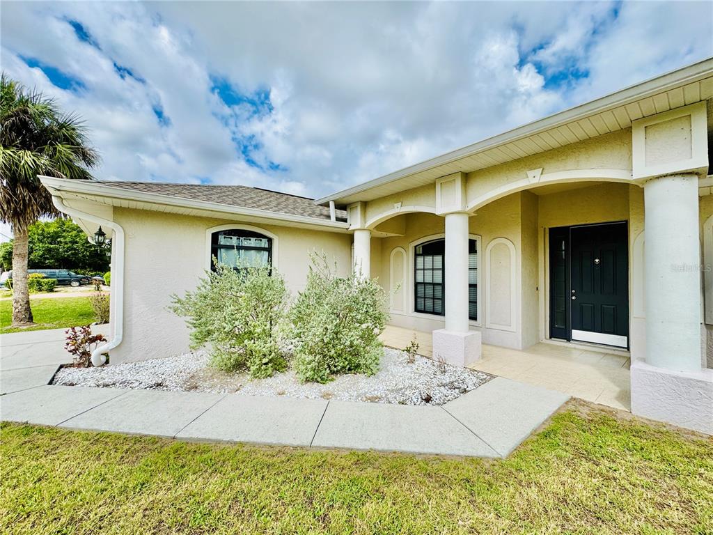 The exterior of a beige house features a covered entryway with columns and landscaping — 3309 N CRANBERRY BOULEVARD, NORTH PORT, FL