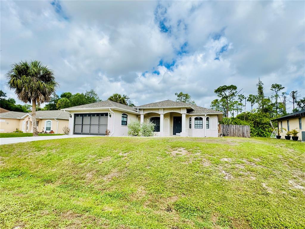 A single-story house with a light-colored exterior, a two-car garage, and a grassy front yard — 3309 N CRANBERRY BOULEVARD, NORTH PORT, FL