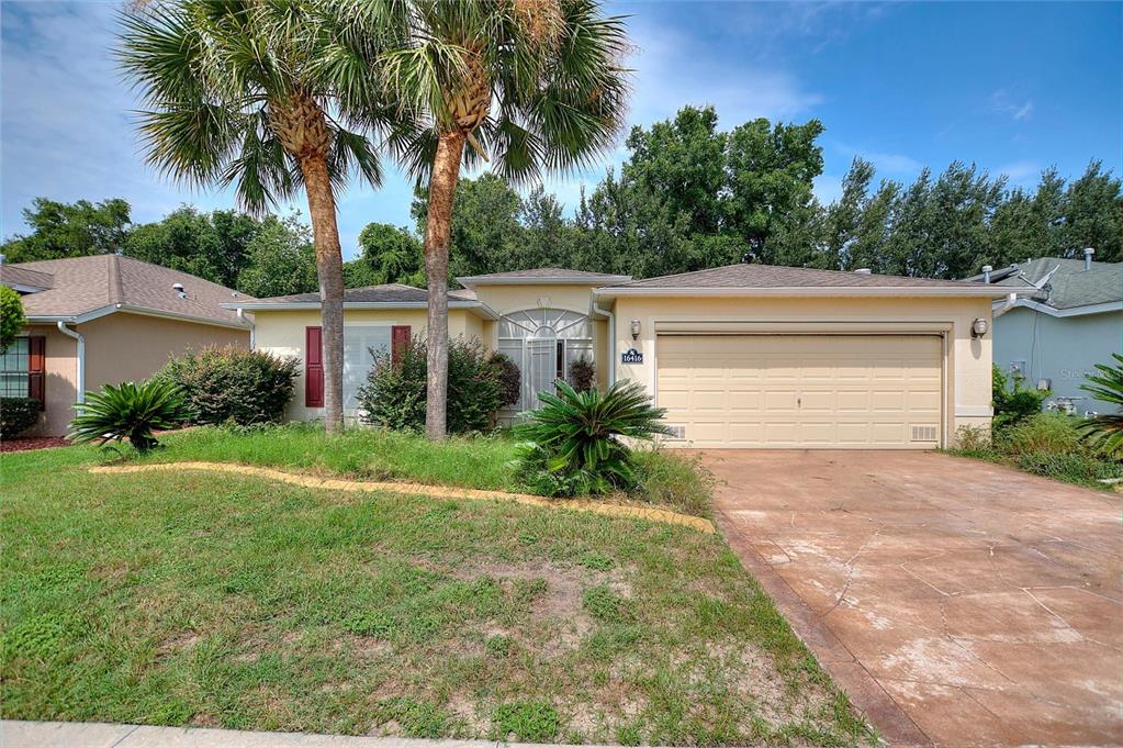 A single-story house with a beige exterior, a two-car garage, and two palm trees — 16416 SW 15TH COURT, OCALA, FL
