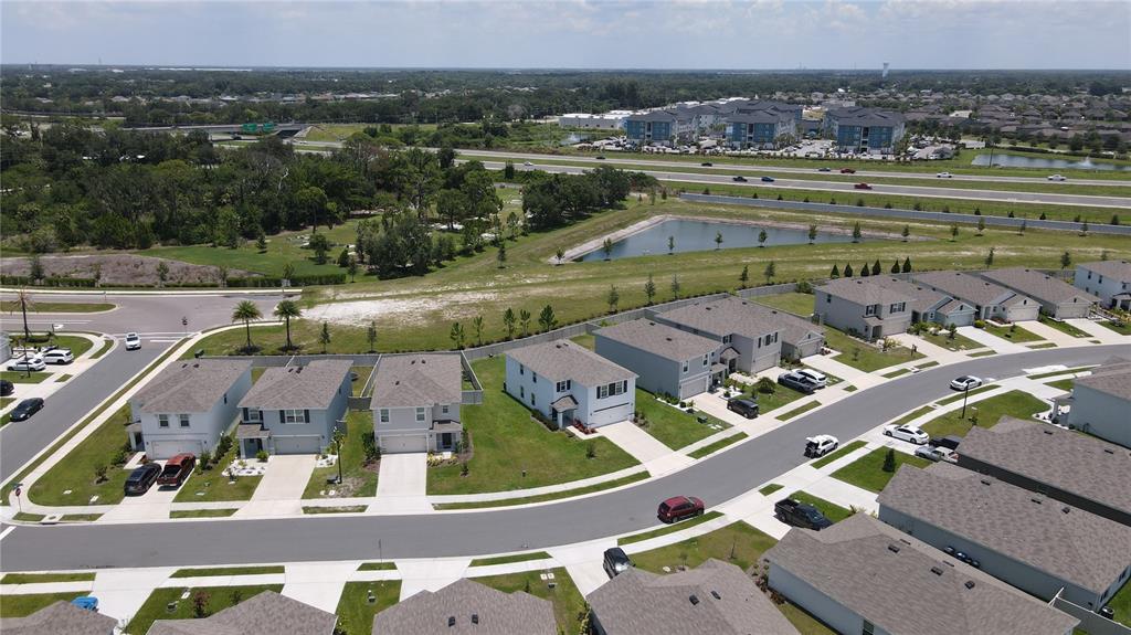 An aerial view shows a suburban neighborhood with houses, a retention pond, and a highway — 6330 DISTANT HAZE PLACE, PALMETTO, FL