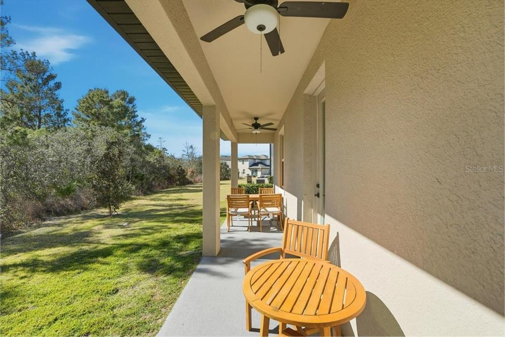 A covered patio features a ceiling fan, outdoor furniture, and a view of the yard — 7792 SOMERSWORTH DRIVE, KISSIMMEE, FL