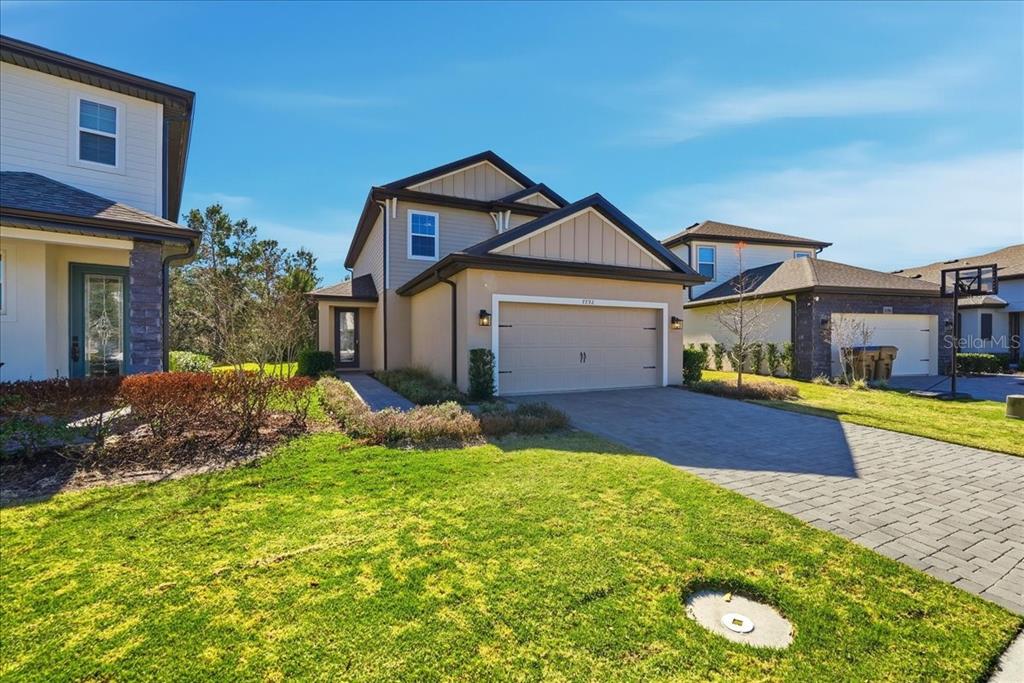 A two-story suburban house with a tan stucco exterior, a two-car garage, and a driveway — 7792 SOMERSWORTH DRIVE, KISSIMMEE, FL