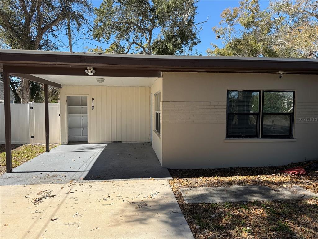 A single-story house exterior features a concrete carport, a storage closet, and a brick facade — 208-210-212 ELIZABETH AVENUE UNIT A,B, CLEARWATER, FL