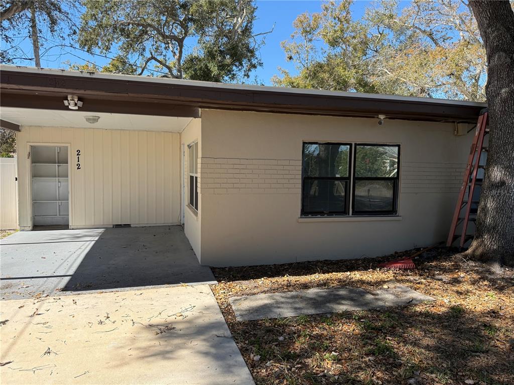 A beige house exterior features a carport, a front door, and a large window — 208-210-212 ELIZABETH AVENUE UNIT A,B, CLEARWATER, FL