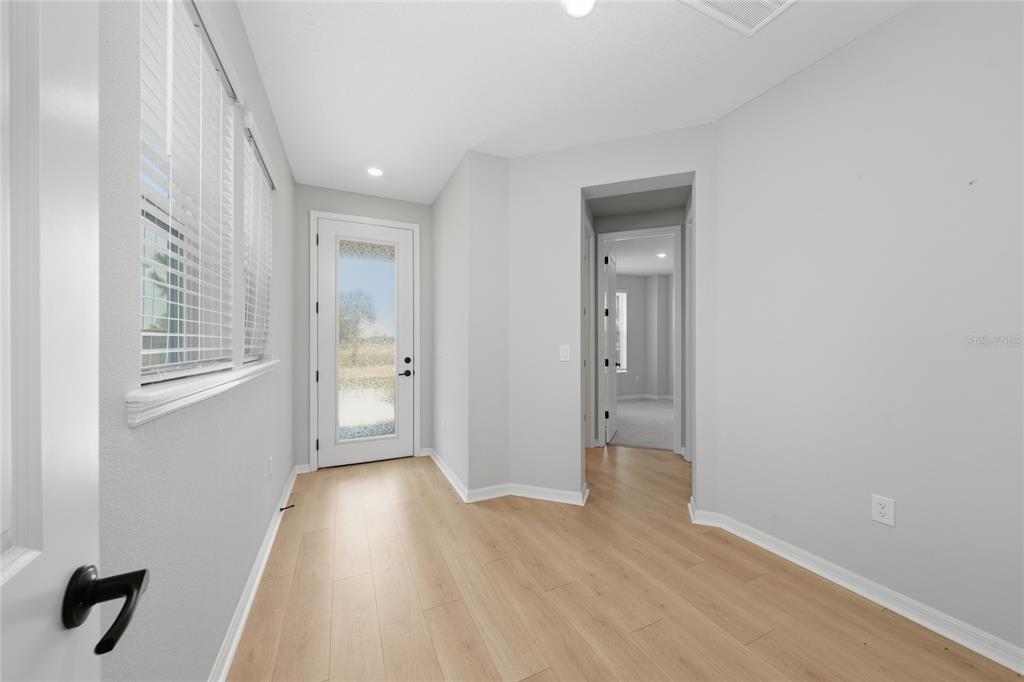 A bright entryway with light wood-look flooring, white walls, and a glass-paneled exterior door — 2914 SAILHOUSE DRIVE, ST CLOUD, FL