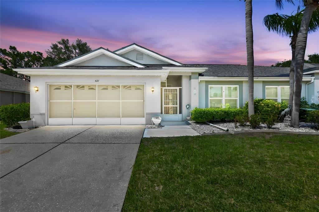 A single-story house with a white garage door, a screened entryway, and a palm tree — 827 MCCALLISTER AVENUE UNIT 55, SUN CITY CENTER, FL