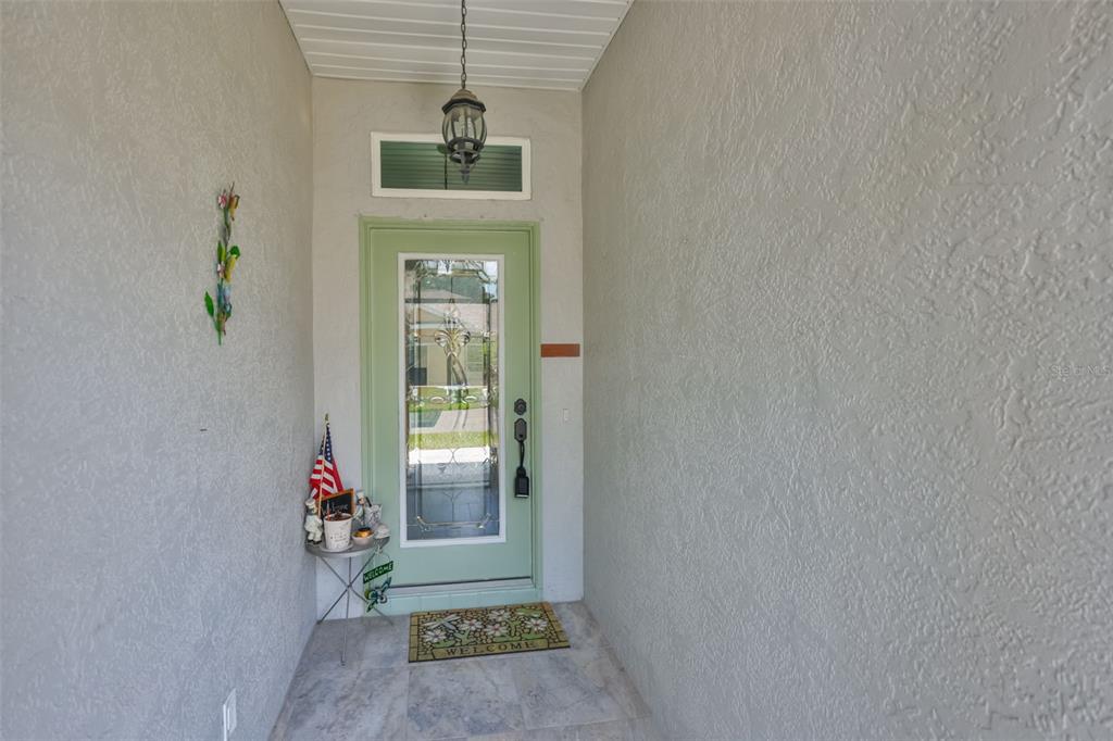 A light green front door with a glass insert sits under a covered entryway — 827 MCCALLISTER AVENUE UNIT 55, SUN CITY CENTER, FL