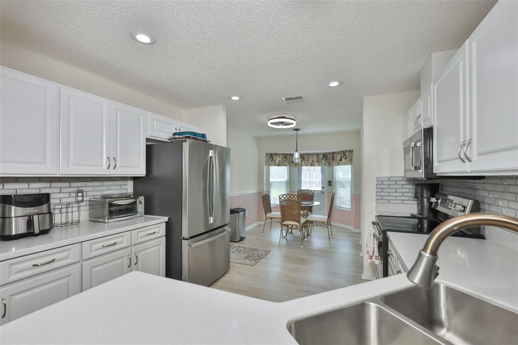 A kitchen with white cabinets, stainless steel appliances, and an adjacent dining area — 827 MCCALLISTER AVENUE UNIT 55, SUN CITY CENTER, FL
