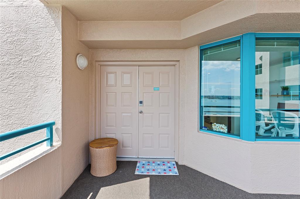 A beige double door entrance with a small wicker stool and a patriotic welcome mat — 1520 GULF BOULEVARD UNIT 1807, CLEARWATER BEACH, FL
