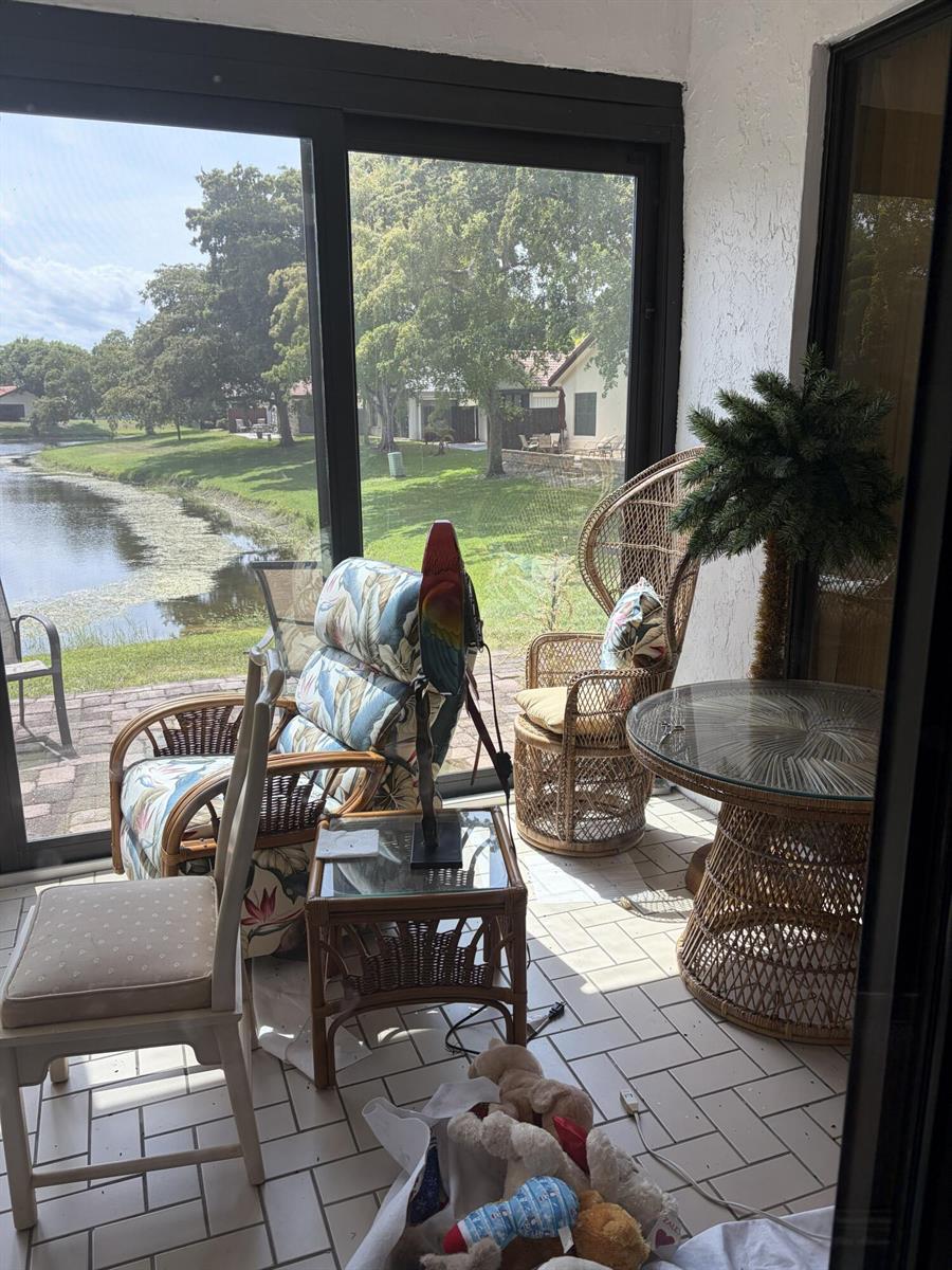 A sunroom with wicker furniture, tile flooring, and a view of a pond — 4807 Boxwood Circle, Boynton Beach FL 33436, BOYNTON BEACH, FL