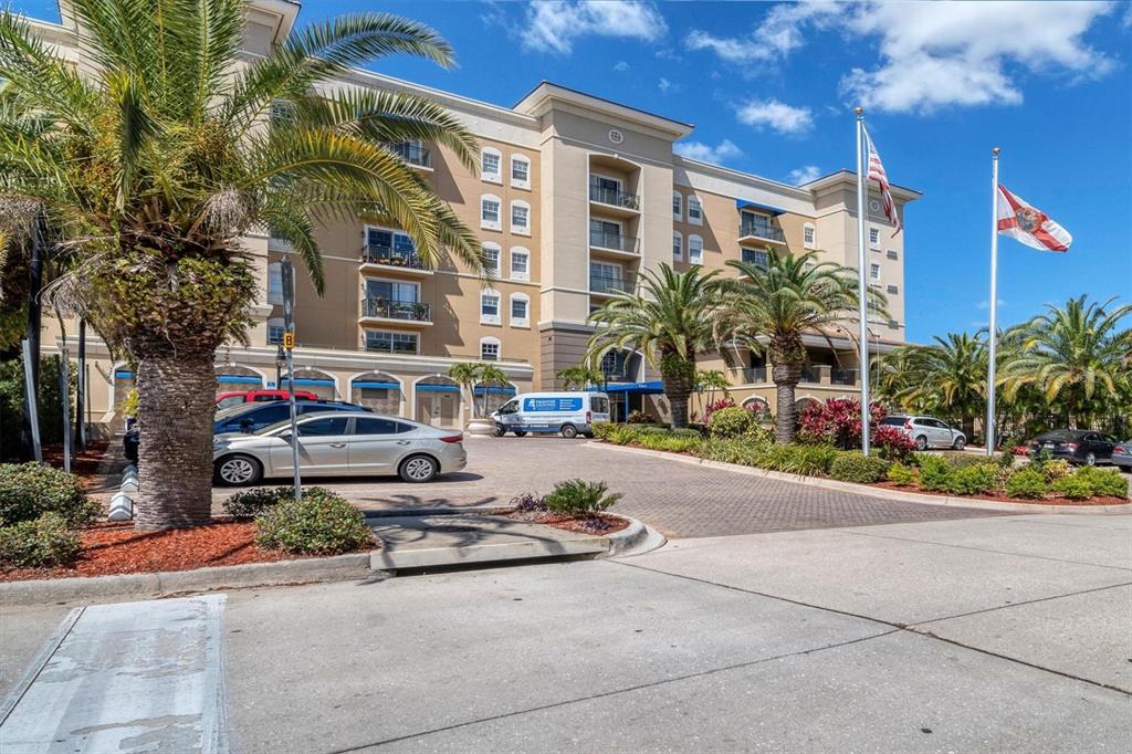 A multi-story beige apartment building with palm trees and a paved parking lot in front — 1064 N TAMIAMI TRAIL UNIT 1527, SARASOTA, FL