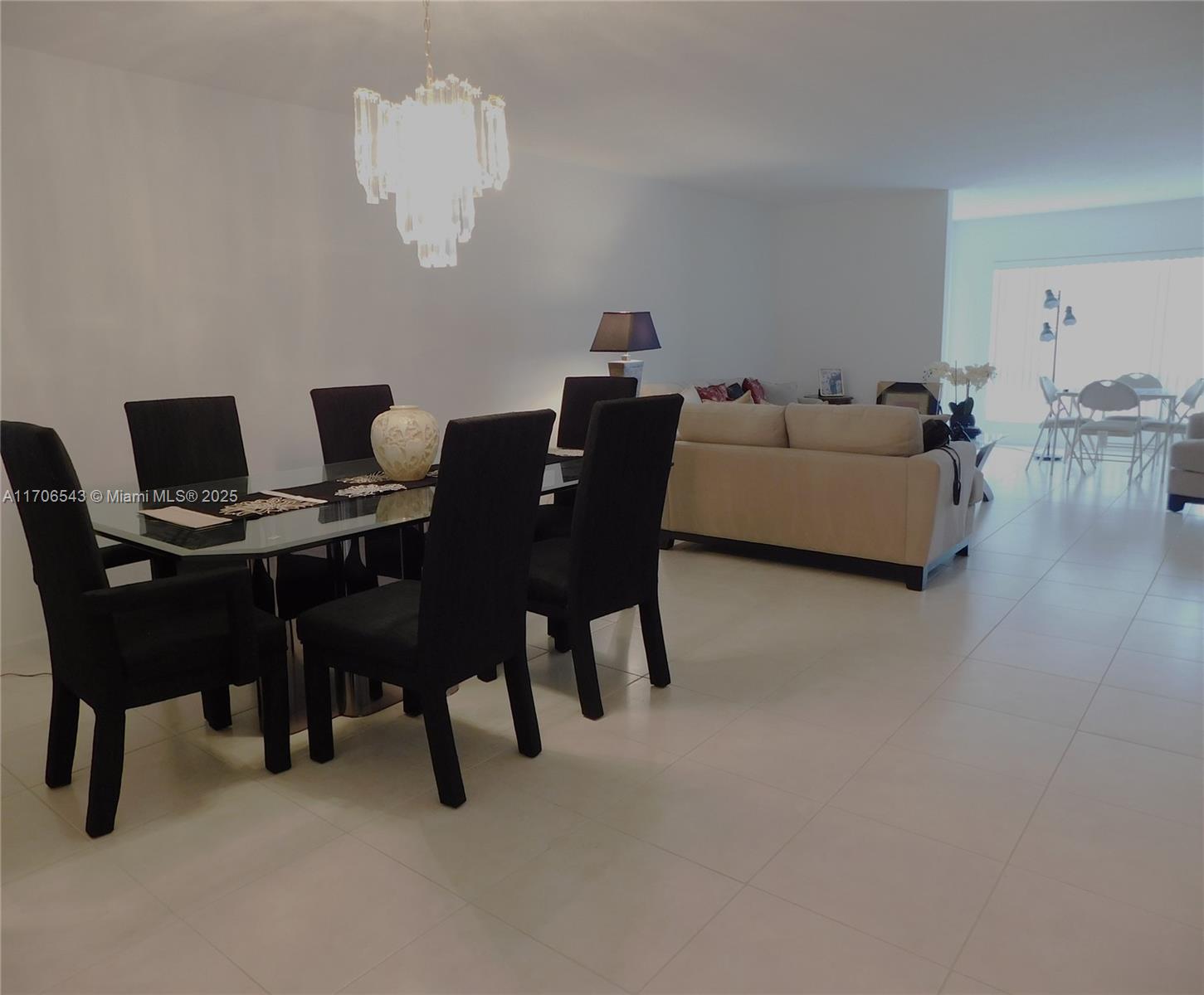 A dining area with a glass table and black chairs sits adjacent to a living room — 5749 Gemstone Ct # 307, Boynton Beach FL 33437, BOYNTON BEACH, FL