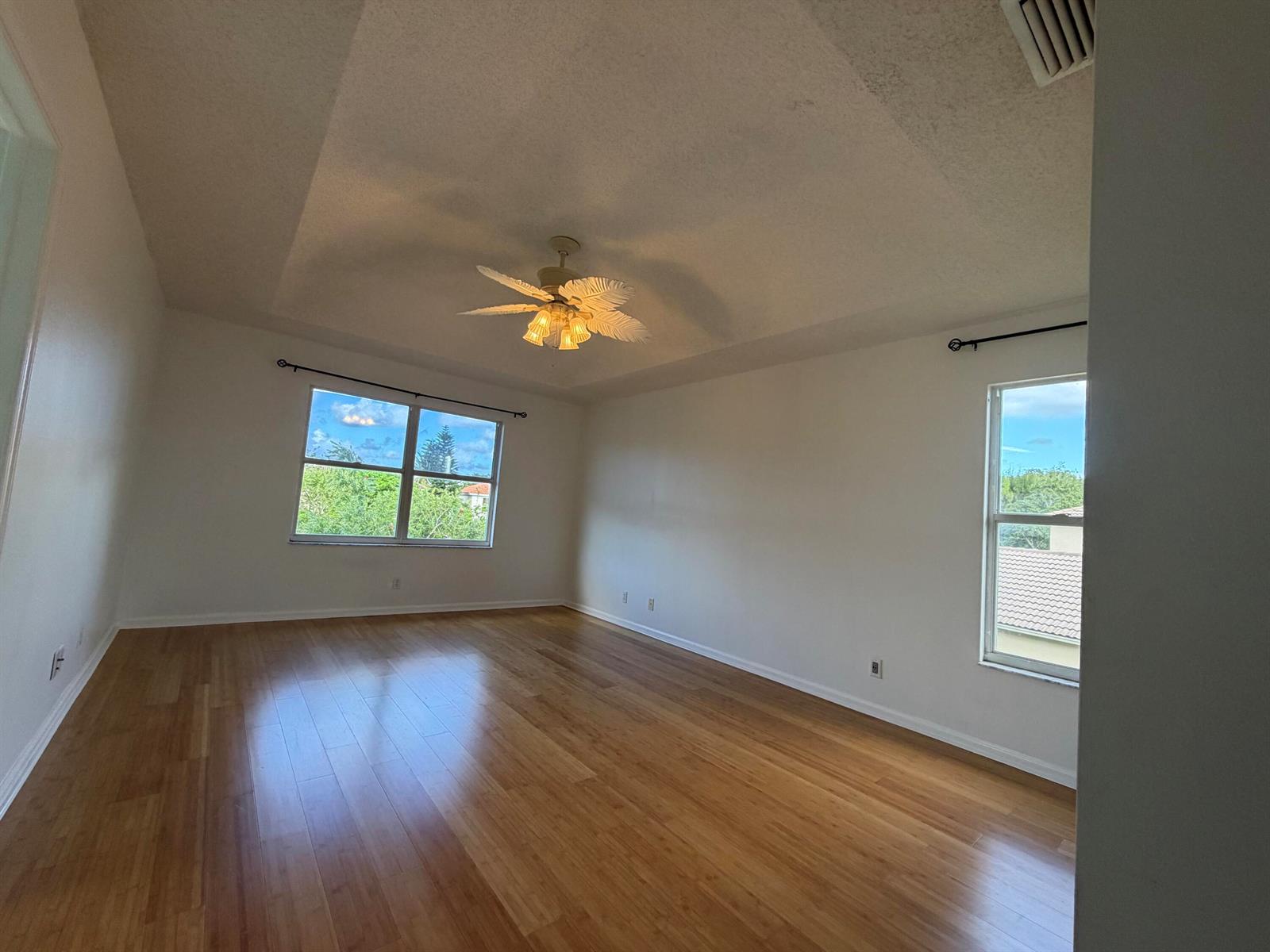An empty room with light wood flooring, white walls, a ceiling fan, and two windows — 1848 Capeside, Wellington FL 33414, WELLINGTON, FL