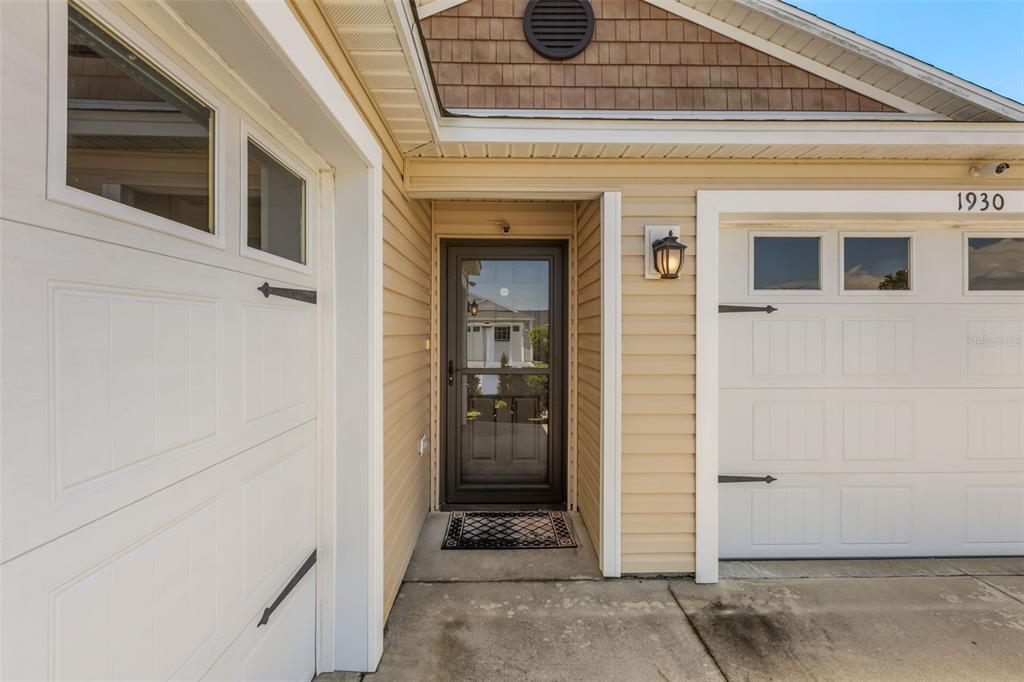 The exterior view shows a front door flanked by two garage doors with windows — 1930 RHETT ROAD, THE VILLAGES, FL