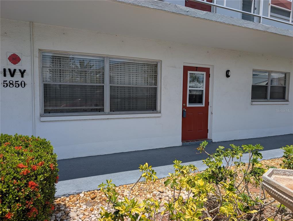 Exterior view of a white building with a red door and a large window — 5850 18TH STREET N UNIT 7, ST PETERSBURG, FL