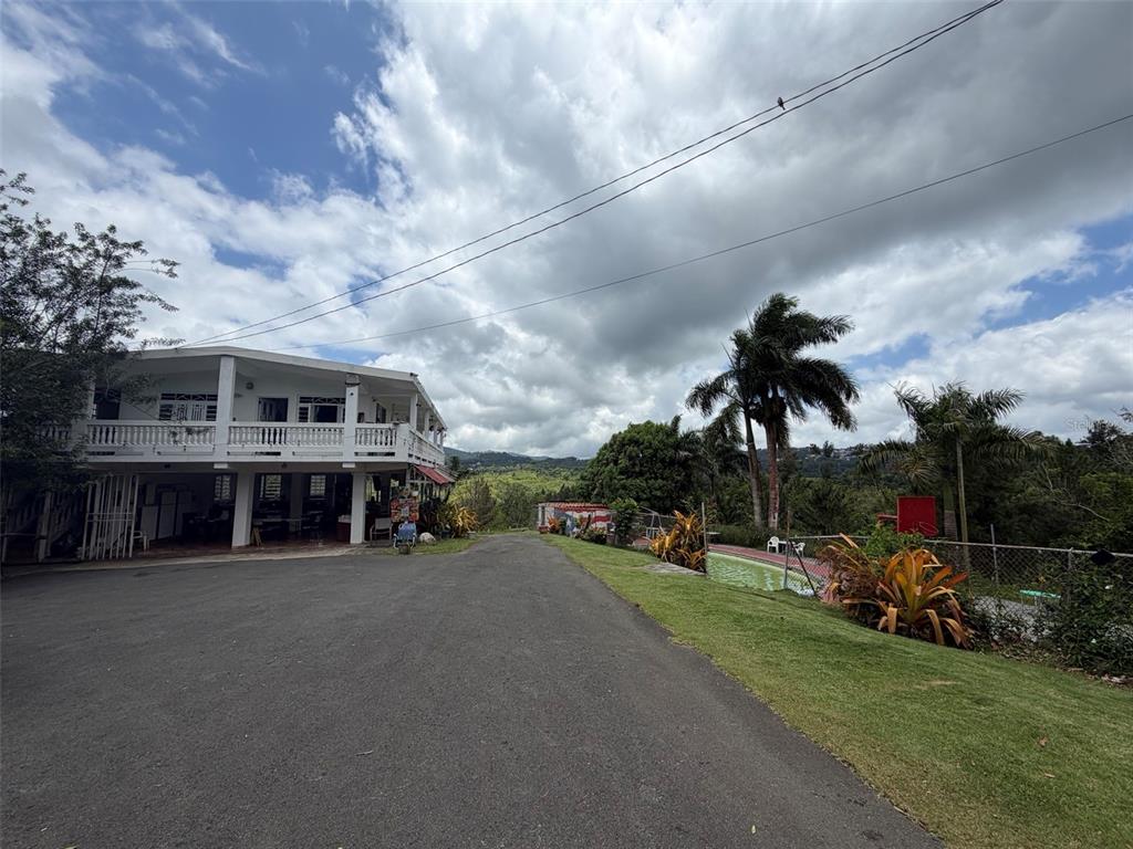 A two-story white building sits beside a paved driveway, a grassy lawn, and palm trees — PR-172 KM 7.5 HACIENDA EL REMANSO, CAÑABONCITO WARD, CAGUAS, PR