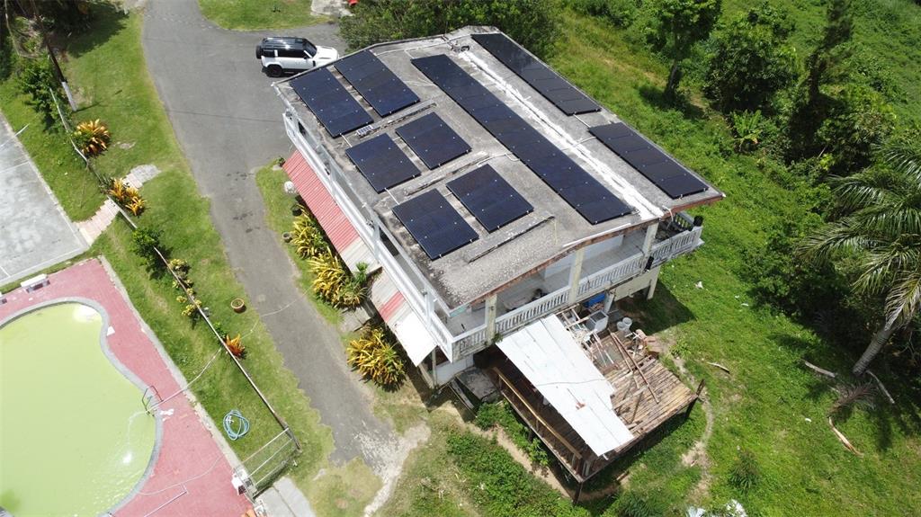 An aerial view shows a multi-story house with a solar panel array on the roof — PR-172 KM 7.5 HACIENDA EL REMANSO, CAÑABONCITO WARD, CAGUAS, PR